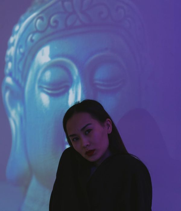 Woman in a calm, balanced pose against a dark background.